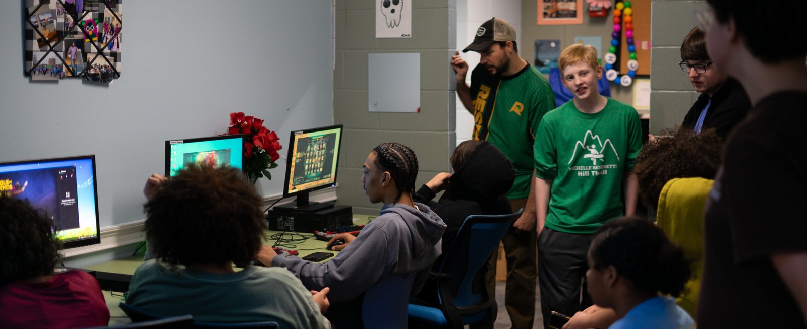 Students and coach gathered around screen. Youth Esports, esports programs for schools, boys & girls club esports, esports education, stem programs, after school esports programs